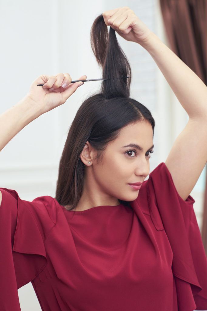 Pevita Pearce menyasak rambut dengan sisir sasak menggunakan baju warna merah