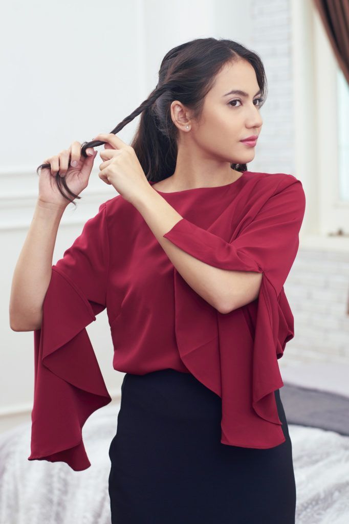 Pevita Pearce memelintir rambut ke samping menggunakan baju merah