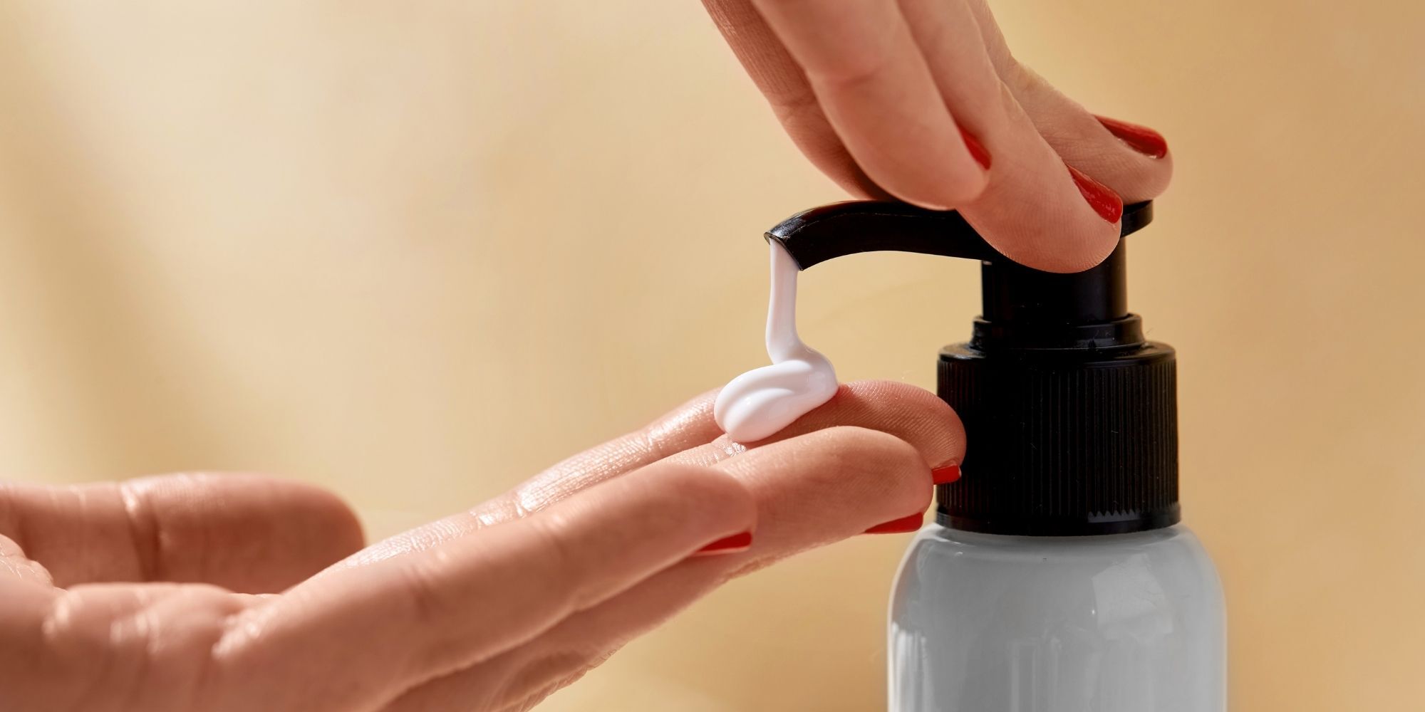 Body lotion yang sedang dituang ke telapak tangan dari botol pump