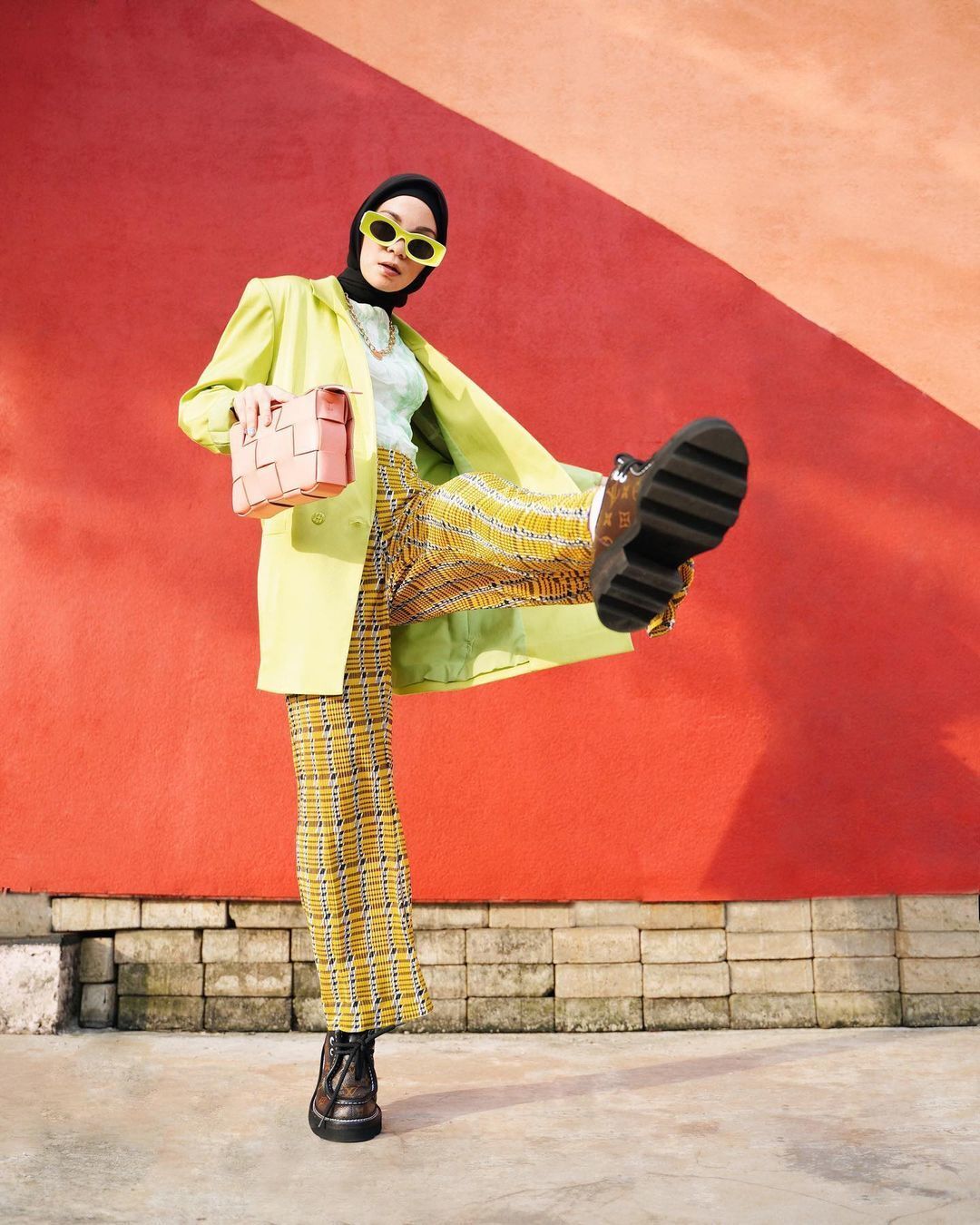 Tantri Namirah selebgram hijab pakai blazer kuning dan hijab hitam bergaya di depan tembok merah