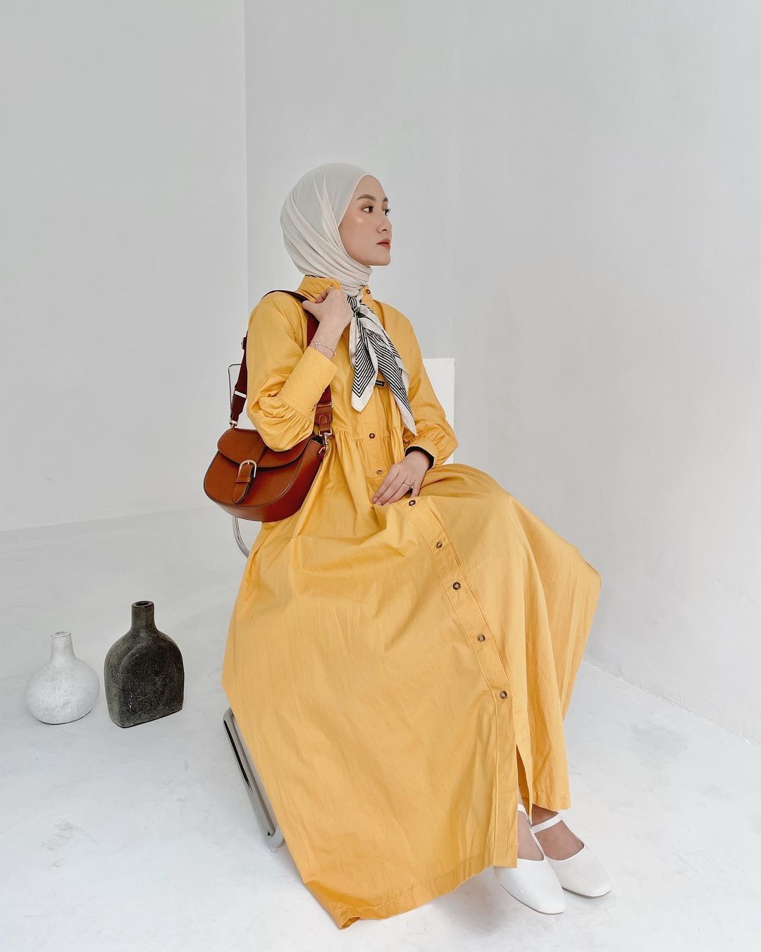 Inasrana selebgram hijab duduk memakai baju kuning dan tas cokelat