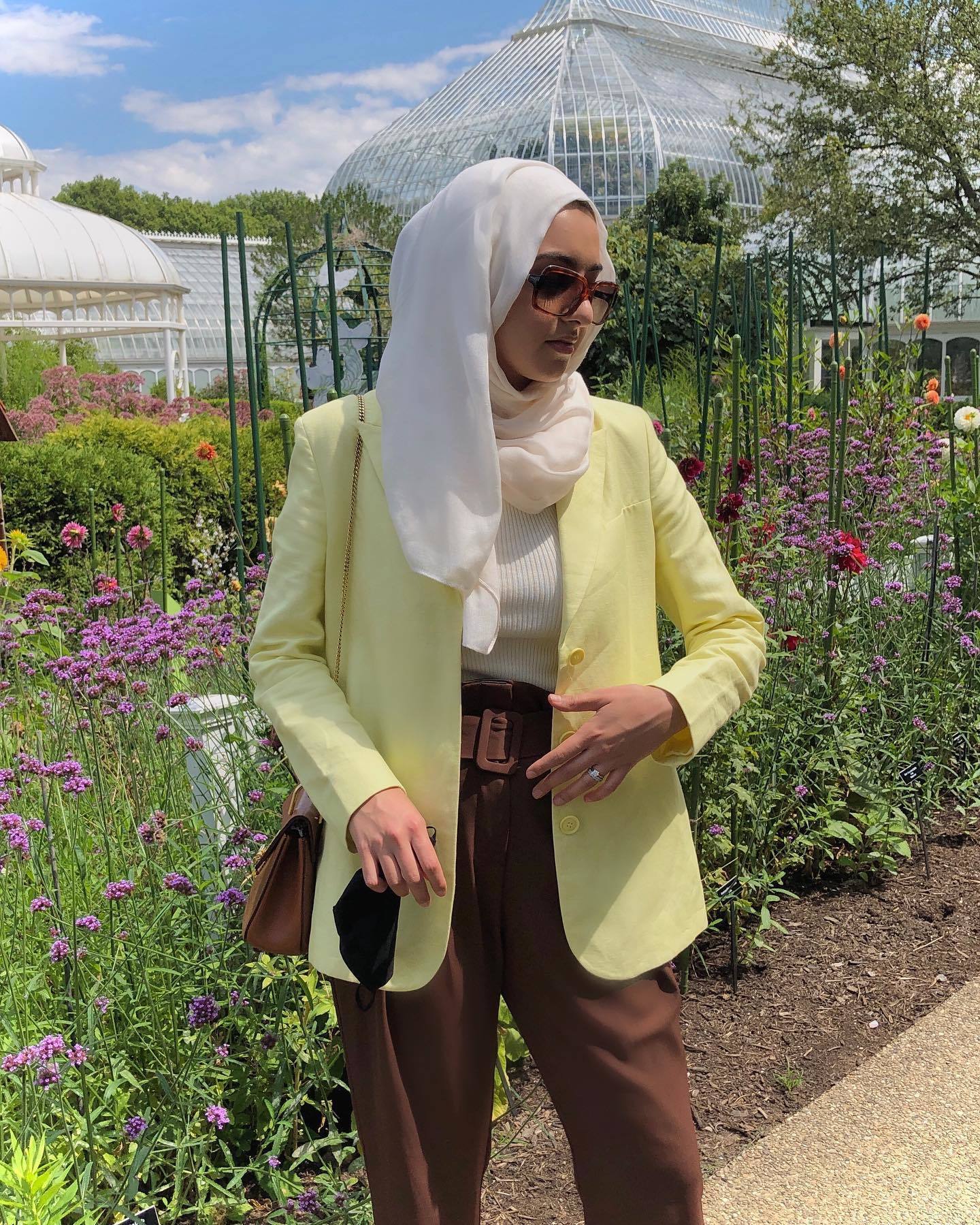 Wanita Kaukasia mengenakan hijab warna putih gading dan blazer warna kuning pastel.