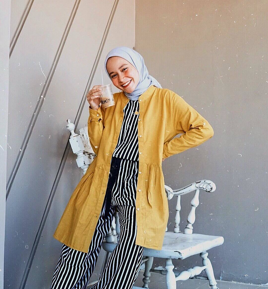 Nissa Chairuninsa selebgram hijab memegang segelas es kopi susu sambil tersenyum