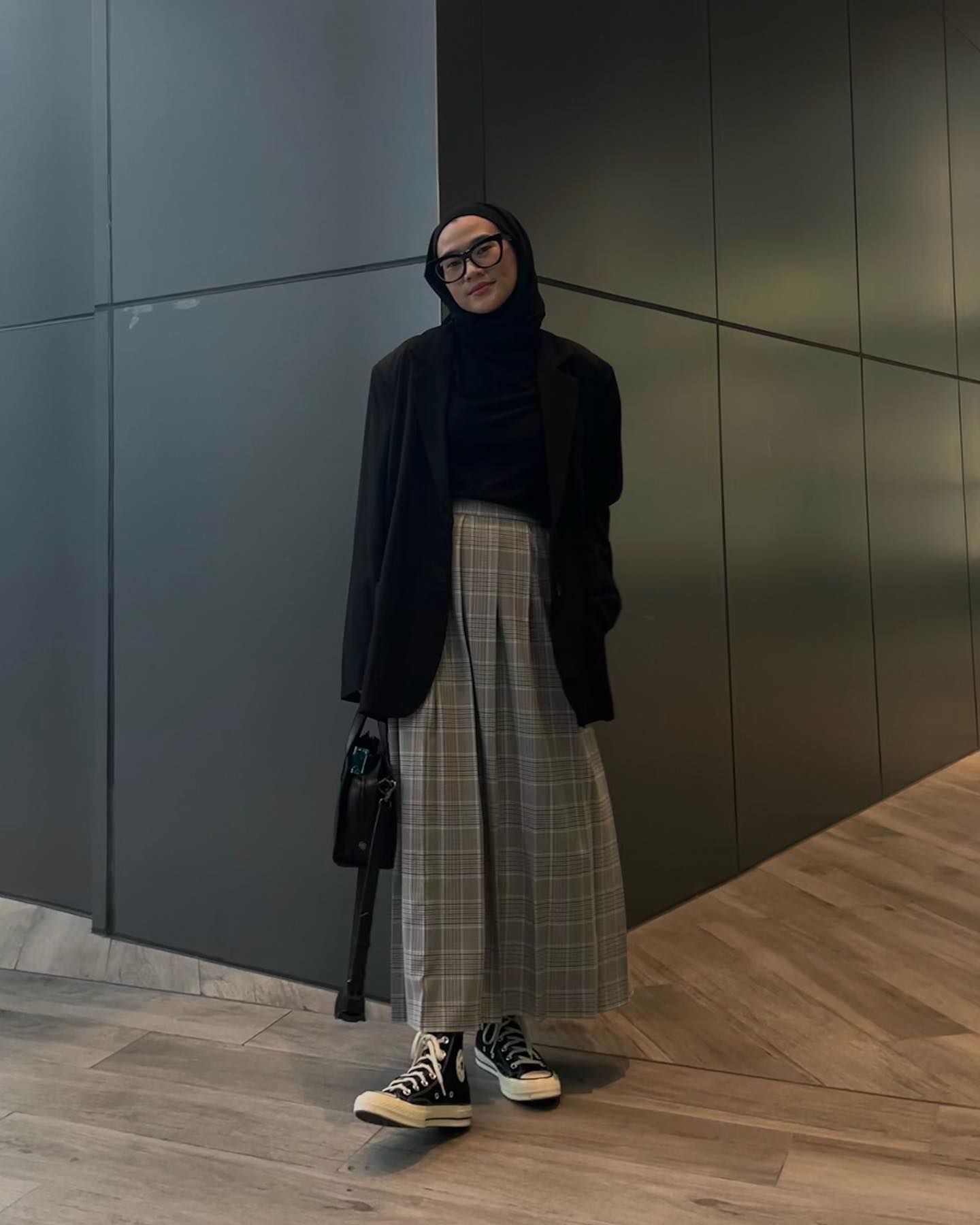 Kenakan blazer hitam dan rok motif kotak-kotak dan padukan dengan jilbab yang warnanya senada. (Foto: Instagram/karina__kamil)