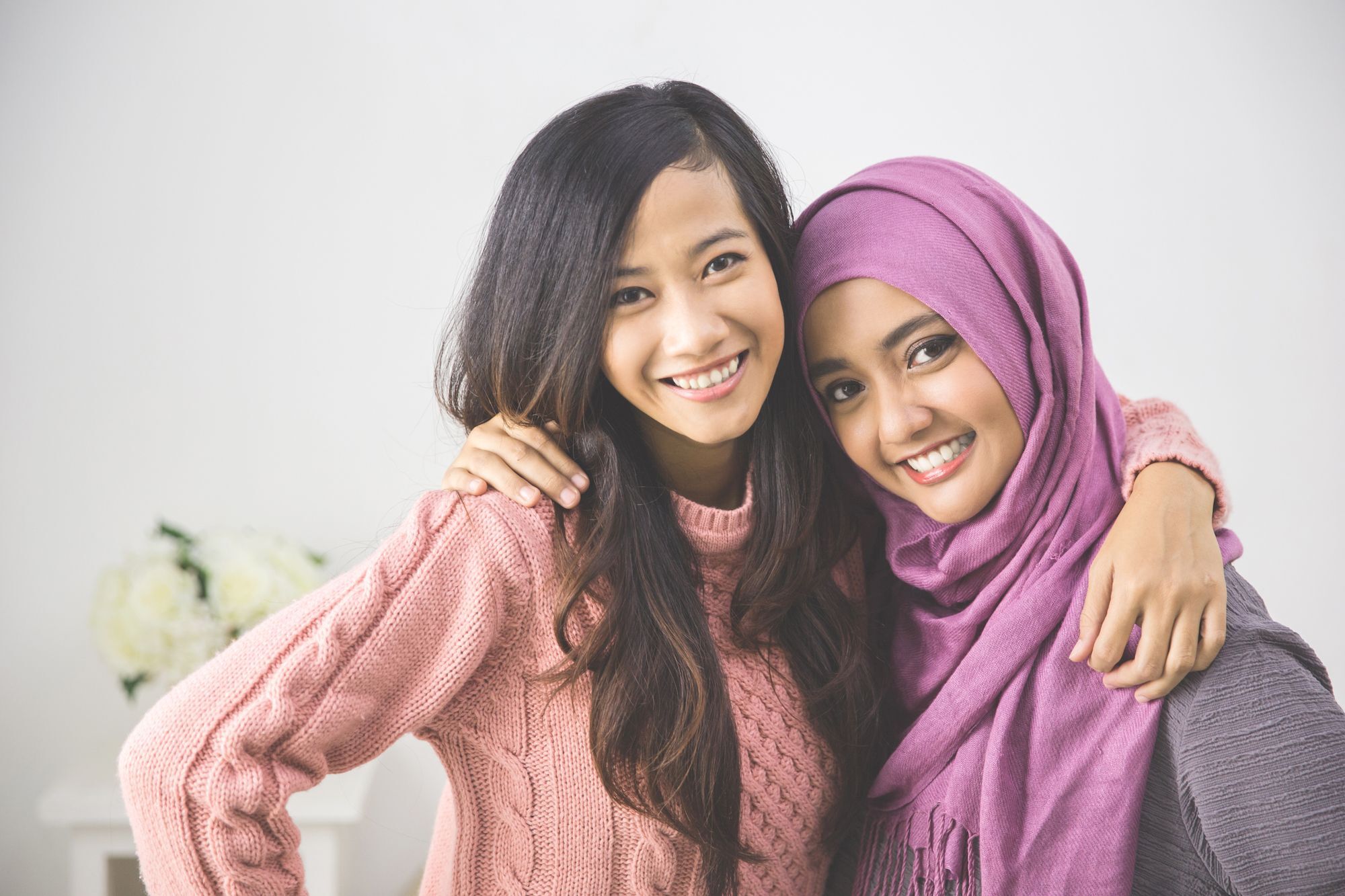 Dua wanita asia dengan warna rambut hitam dan hijab ungu berpelukan