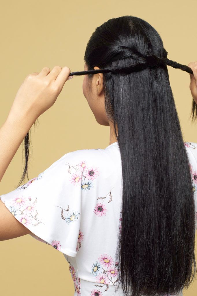 Wanita asia dengan rambut hitam panjang menata rambut dengan gaya knotted bubble ponytail