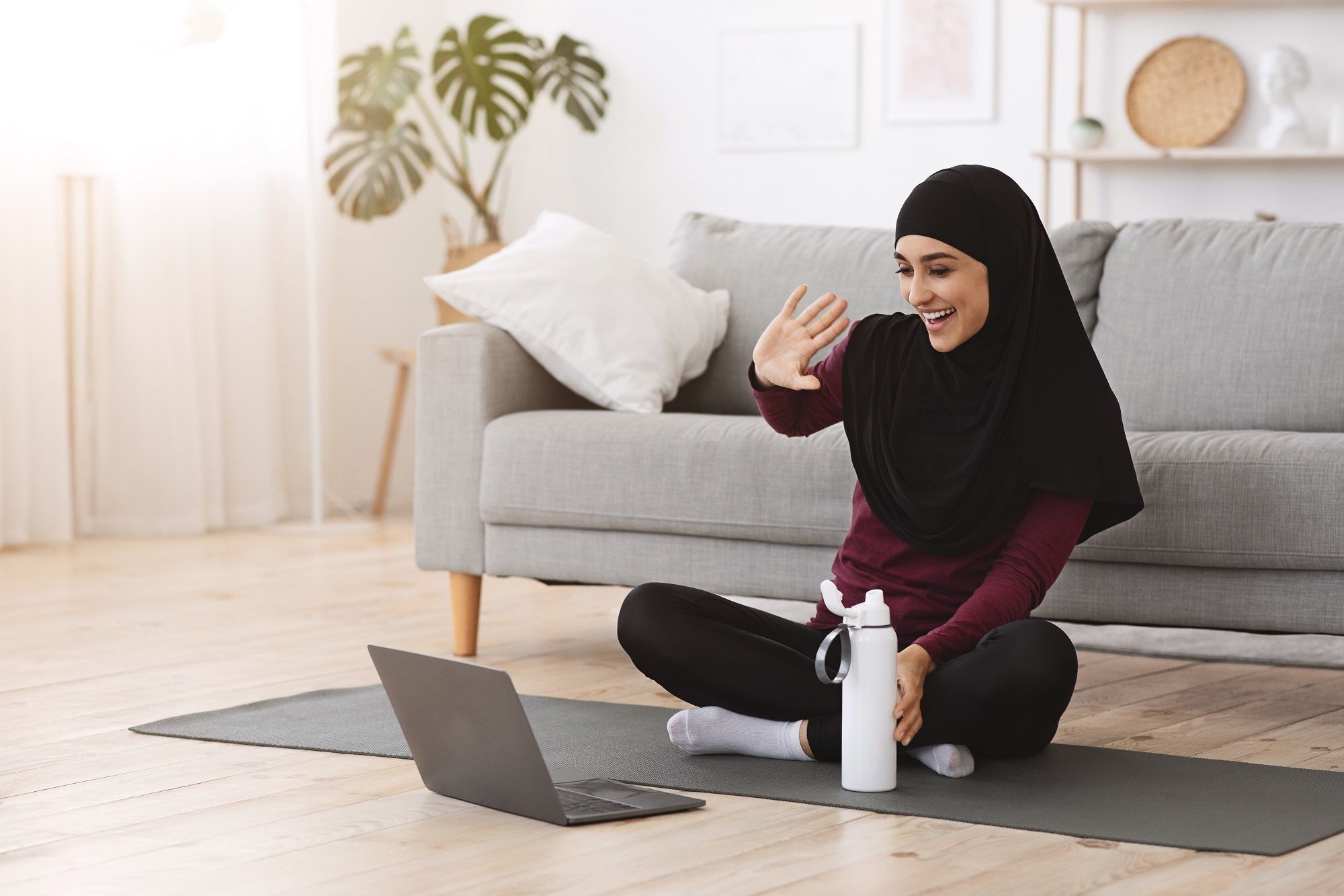 Wanita Asia memakai hijab kaos untuk berolahraga di rumah.