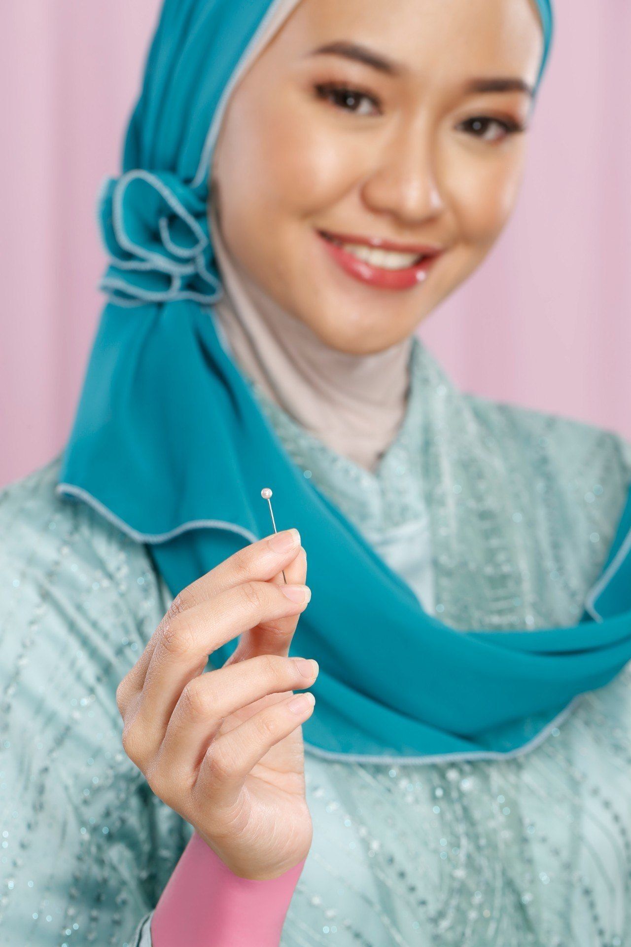 Wanita berhijab memperlihatkan jarum pentul