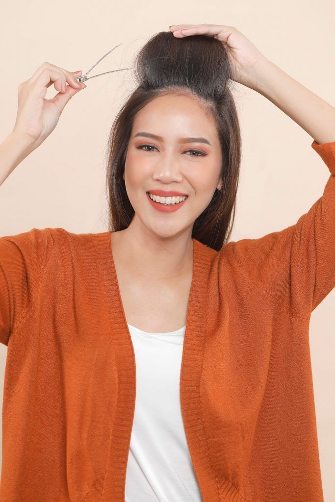 wanita asia sedang menggulung rambut menggunakan rol