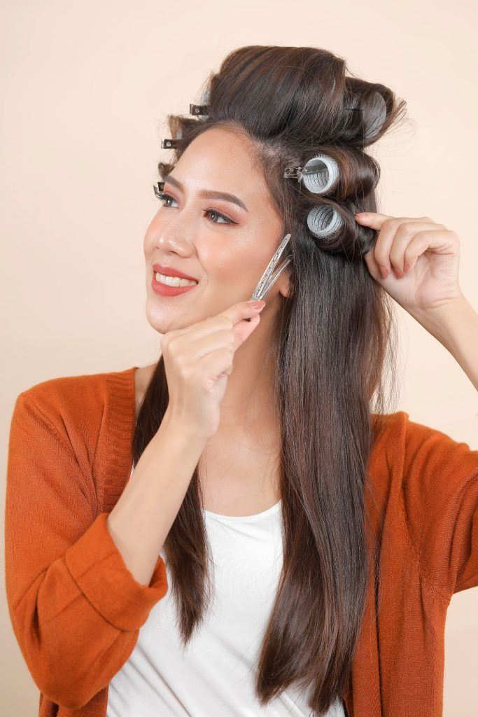 wanita asia sedang menggulung rambut menggunakan rol