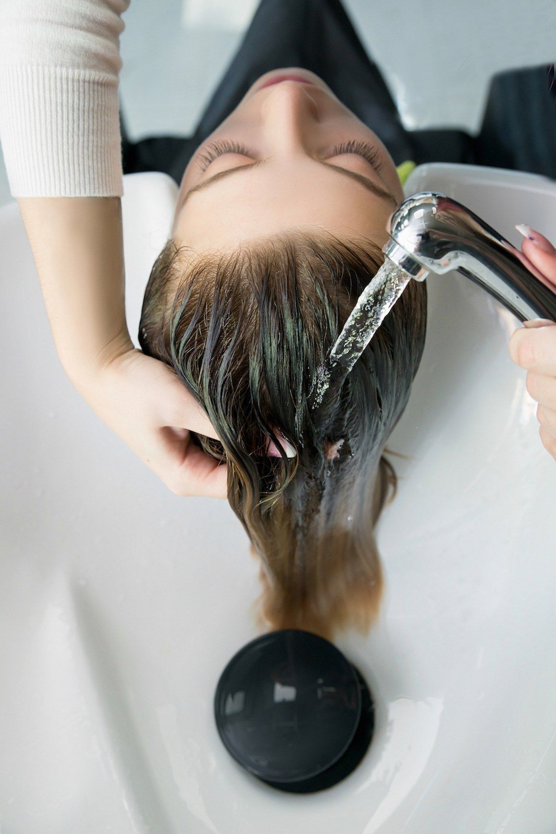 Wanita kaukasia dengan warna rambut cokelat kehijauan keramas dengan air mengalir