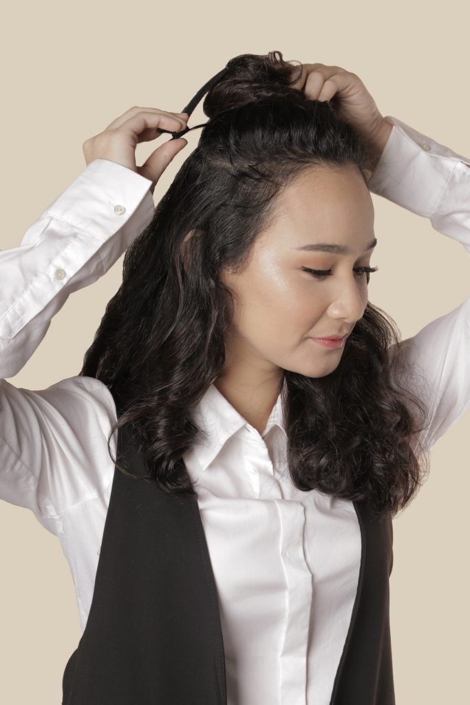 Wanita sedang membuat cepol untuk gaya rambut faux hawk