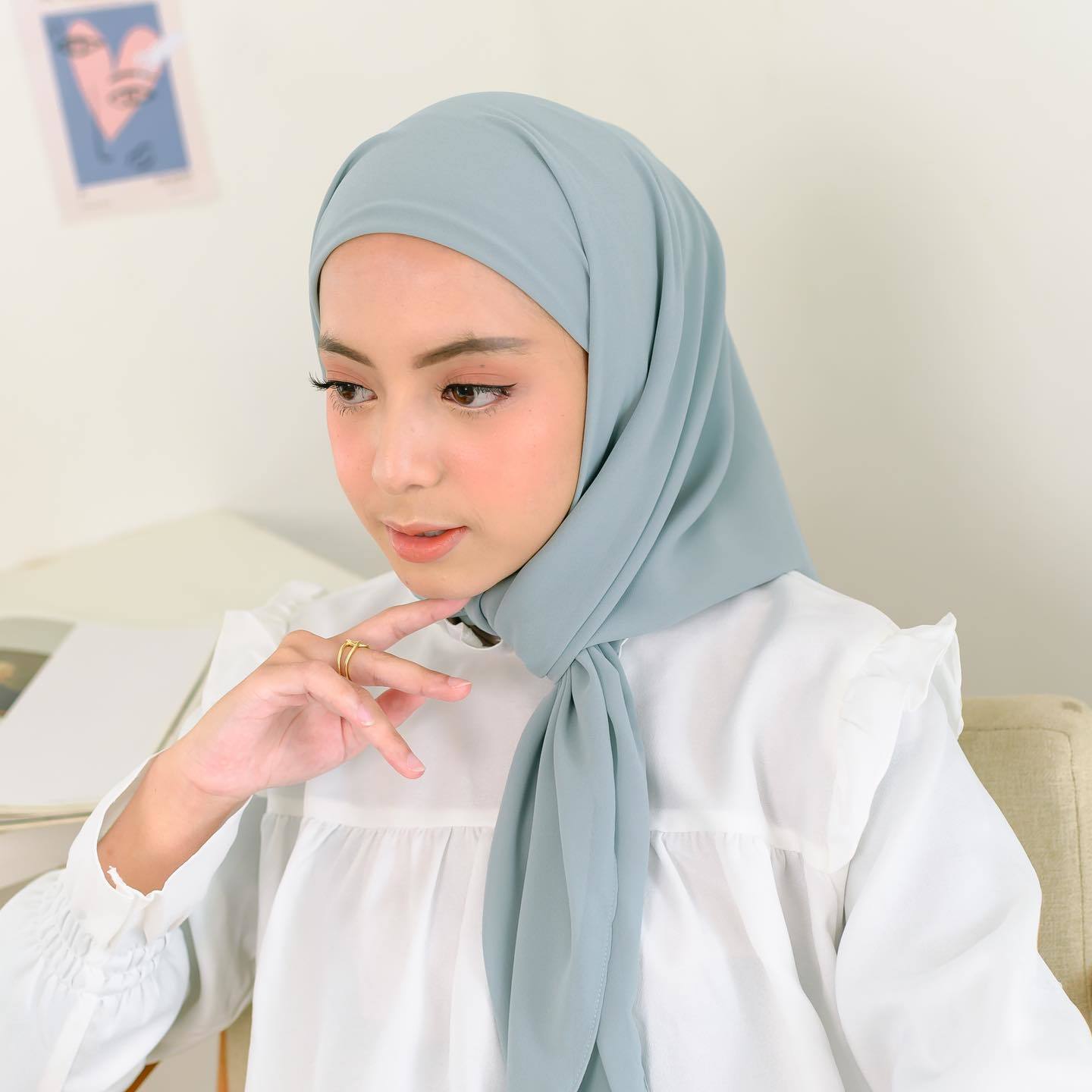 wanita Indonesia kenakan hijab segi empat instan warna biru muda.