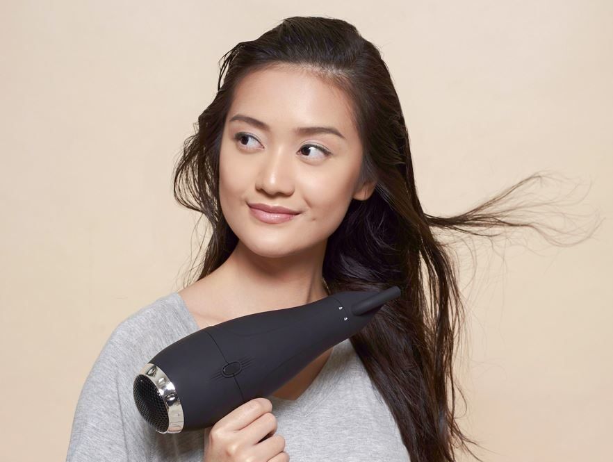 perempuan asia memakai hair dryer untuk mengeringkan rambut panjang