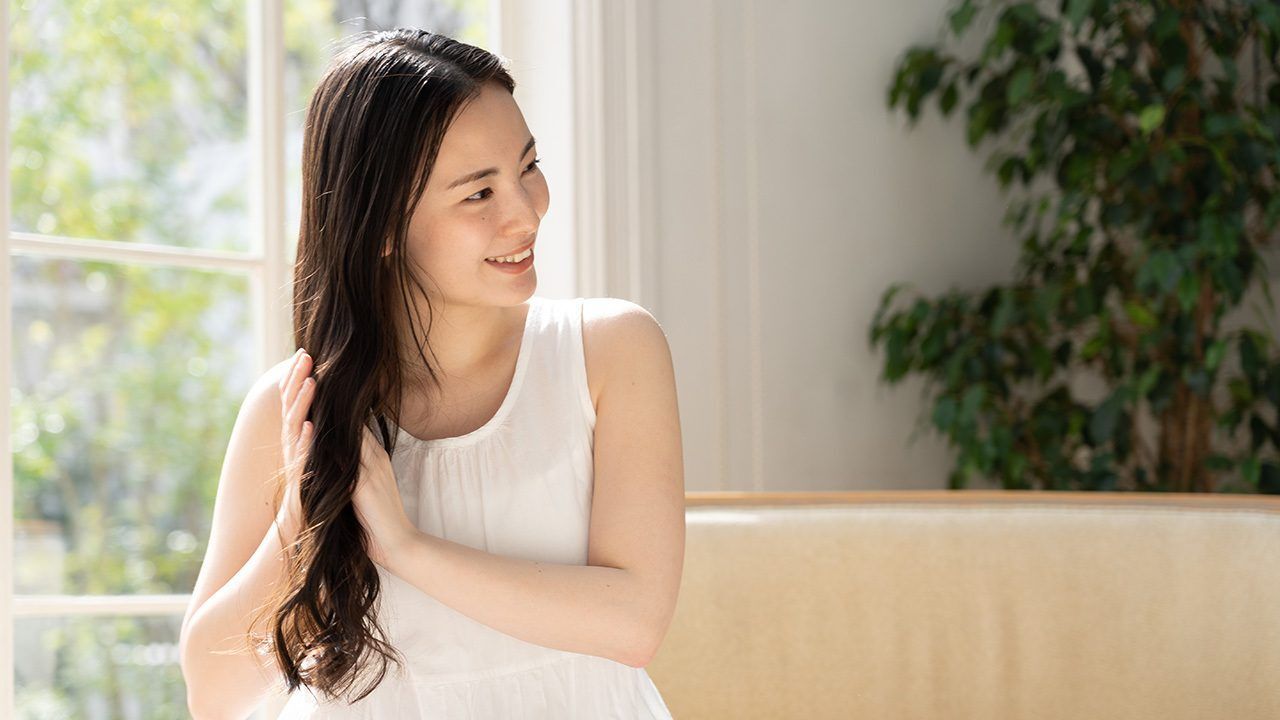 wanita asia sedang menggunakan produk rambut