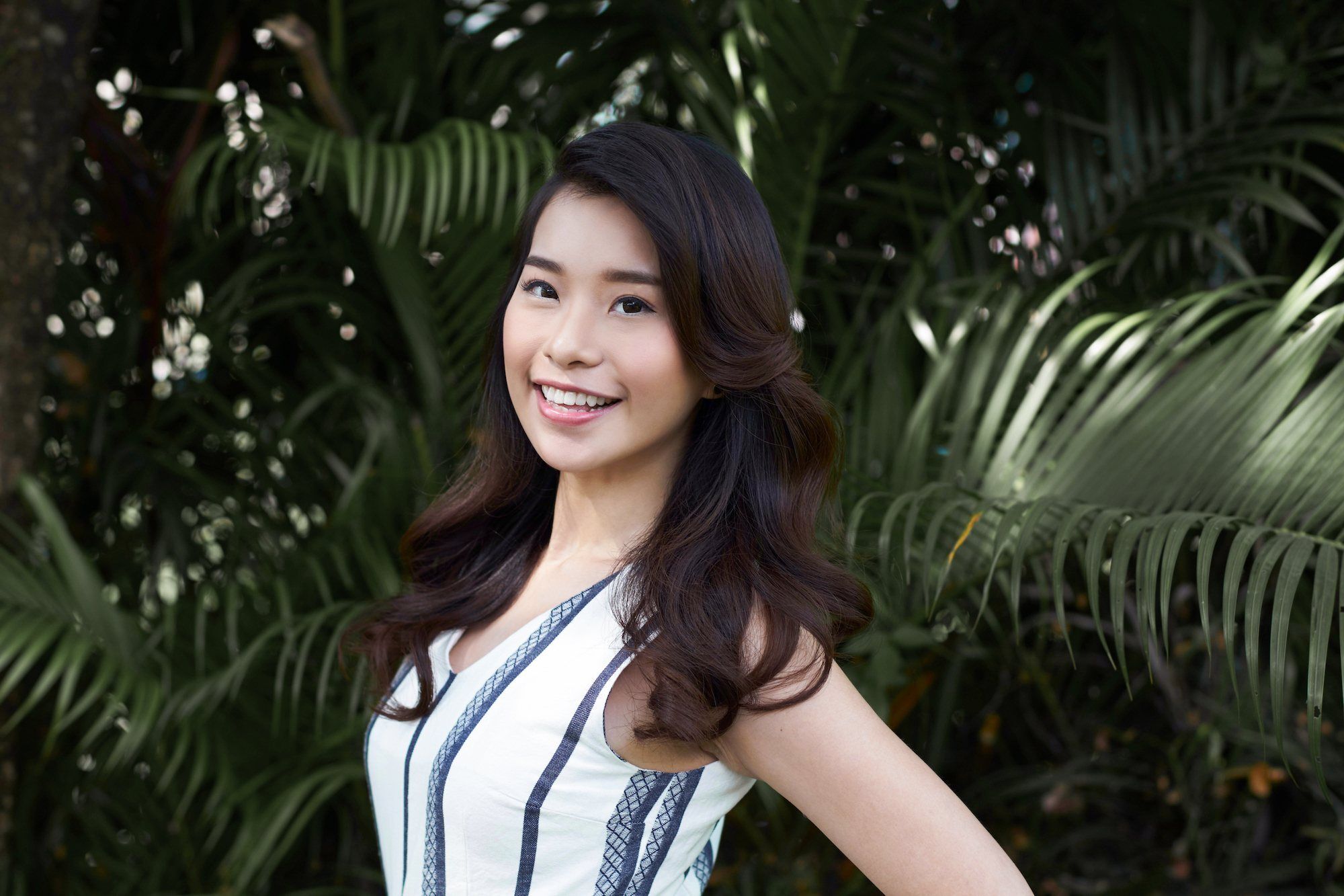 Wanita asia dengan rambut panjang cokelat menggunakan cara menata rambut lebih bervolume