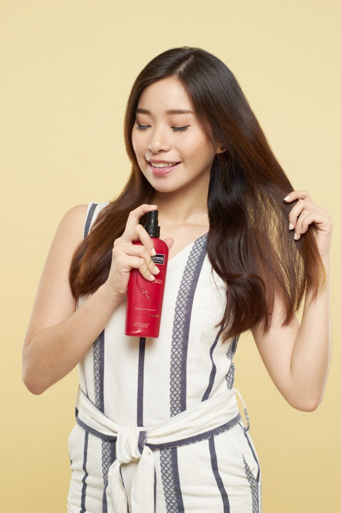 Wanita asia dengan rambut panjang cokelat menggunakan heat protection – cara membuat rambut bervolume