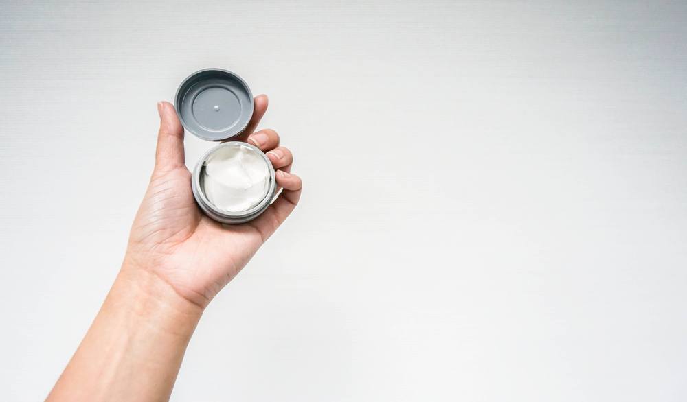 Seorang pria menggenggam wax rambut dengan tekstur yang padat dan terbuat dari lilin.