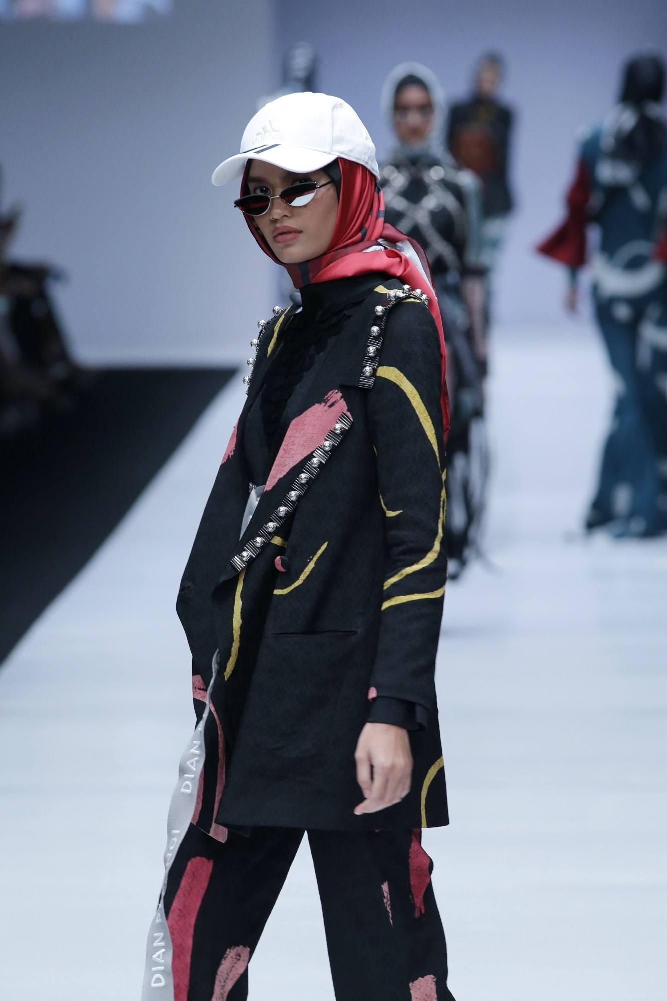 Model berjalan memakai hijab dan topi rancangan Dian Pelangi di JFW 2019