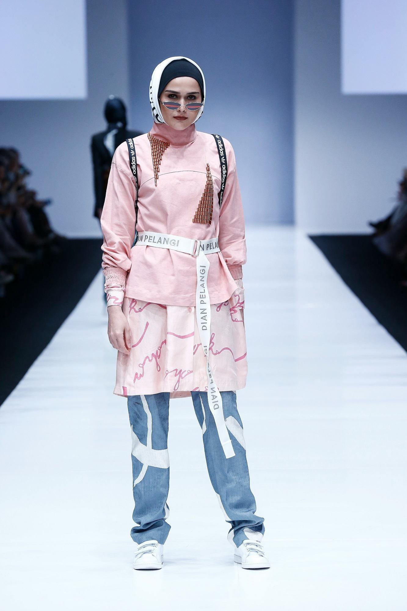 Model berhijab berjalan di catwalk JFW 2019 memakai baju rancangan Dian Pelangi