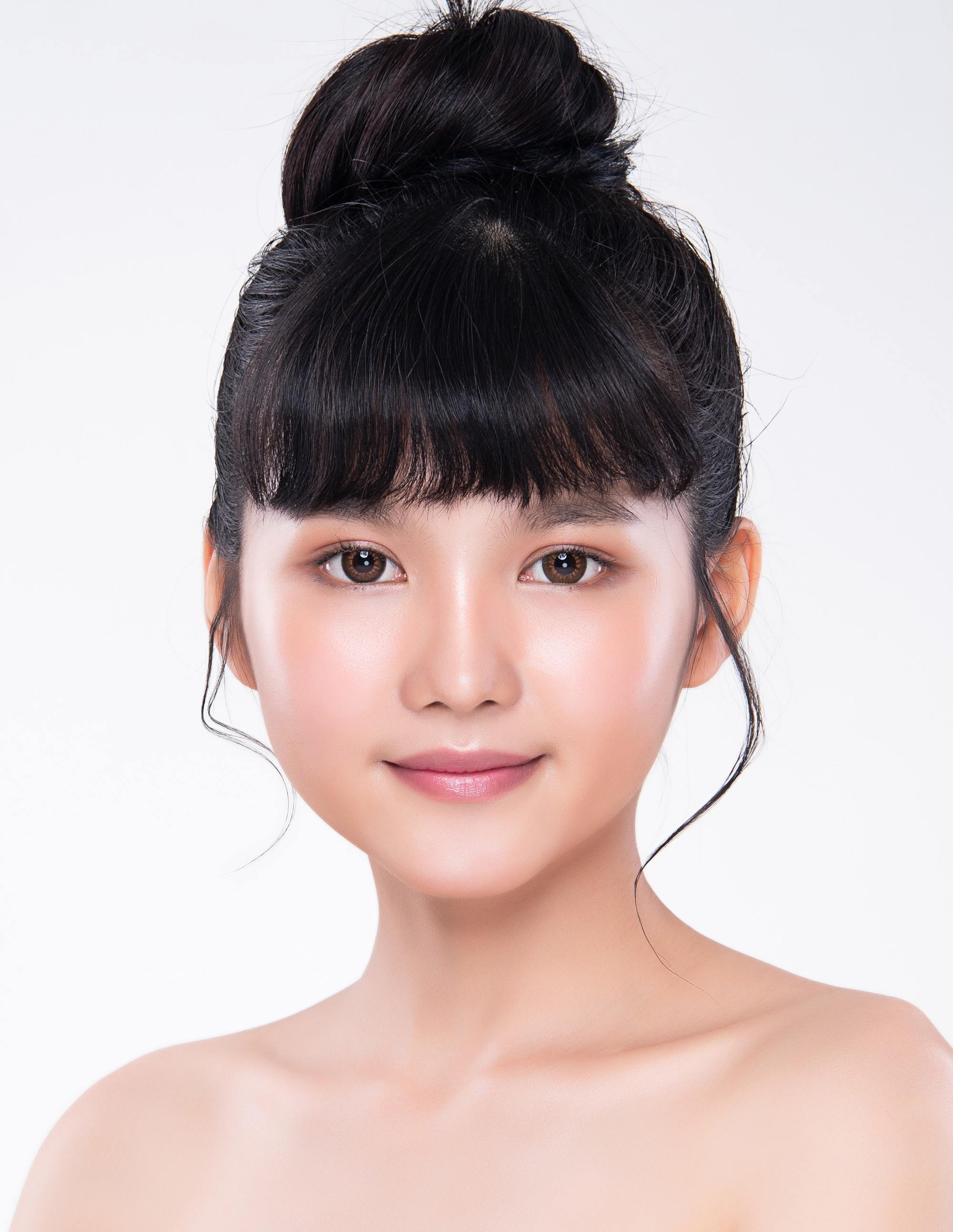 Gaya rambut top knot dengan poni bisa menyamarkan dahi yang lebar, lho. (Foto: Shutterstock)