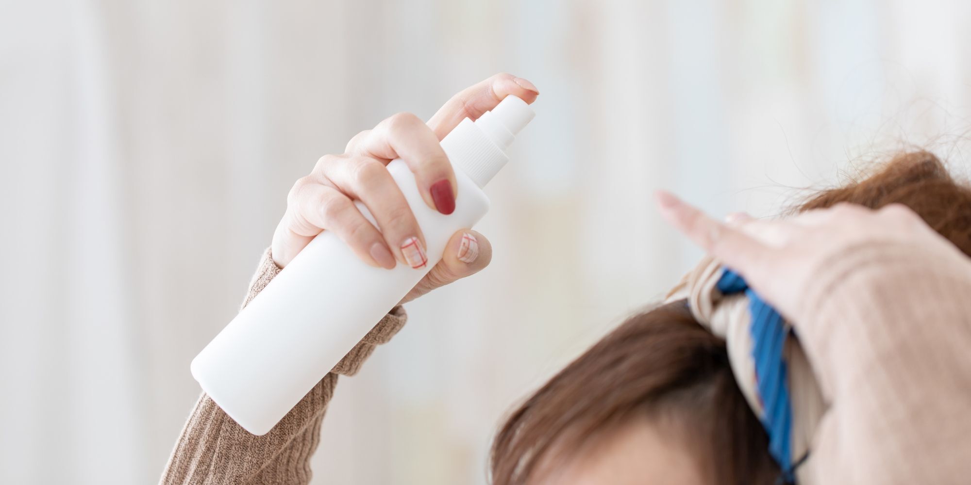 wanita sedang menyemprot parfum rambut