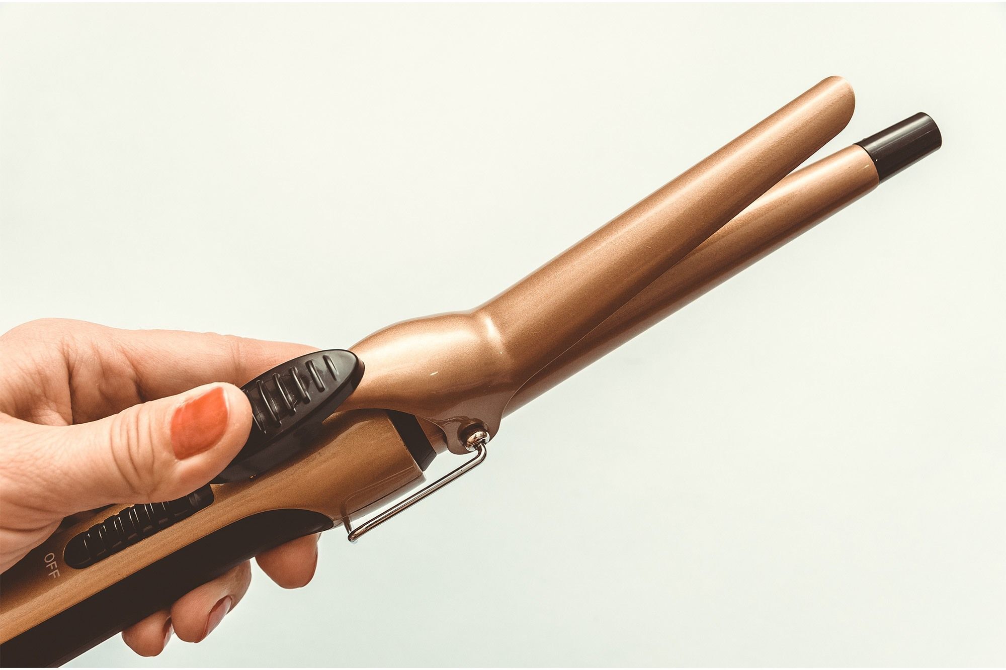 wanita sedang menggunakan curling iron atau catokan keriting dengan penjepit