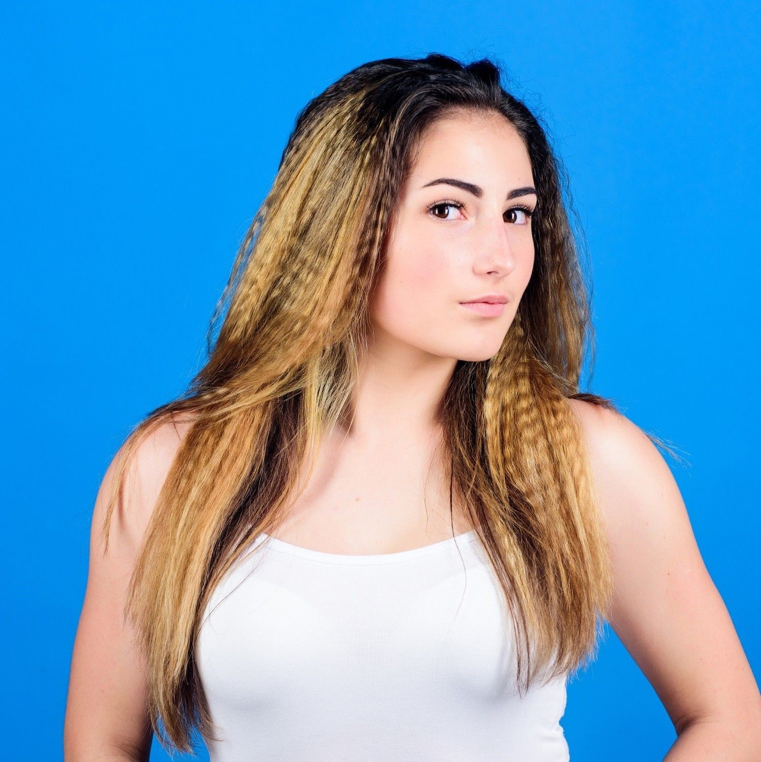 Wanita kaukasia dengan rambut panjang pirang yang dicatok keriting crimped.