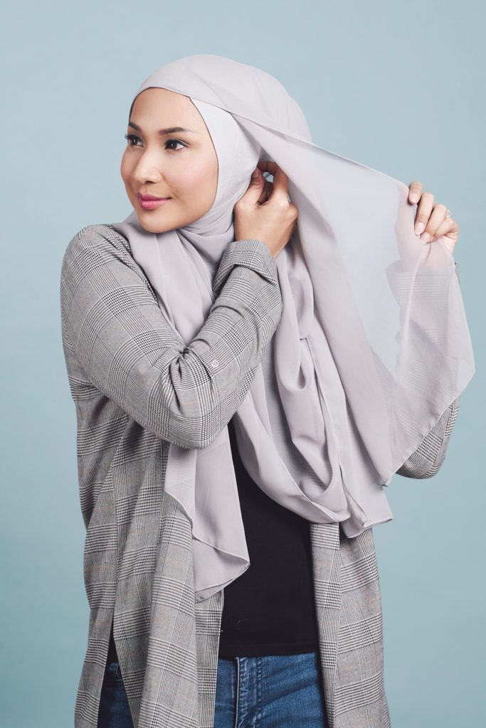 Wanita asia menyematkan jarum pentul pada hijabnya