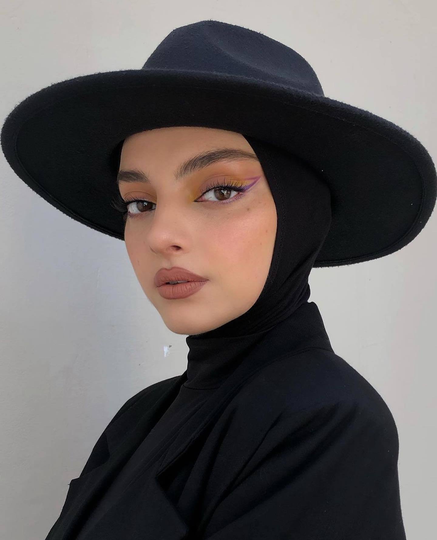 Wanita kaukasia berhijab dan mengenakan topi lebar