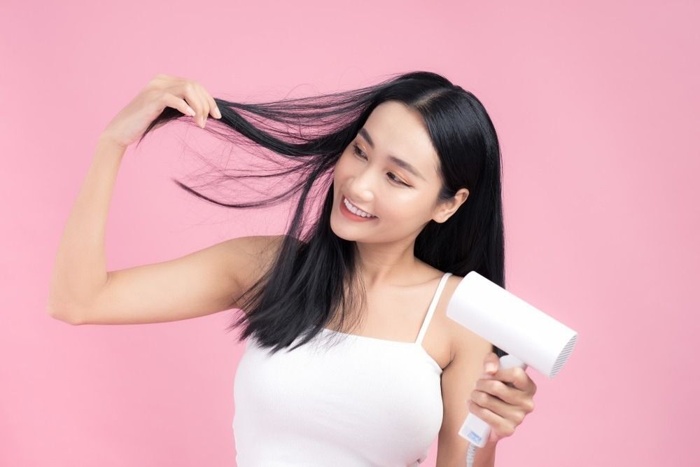 wanita asia sedang mengeringkan rambut