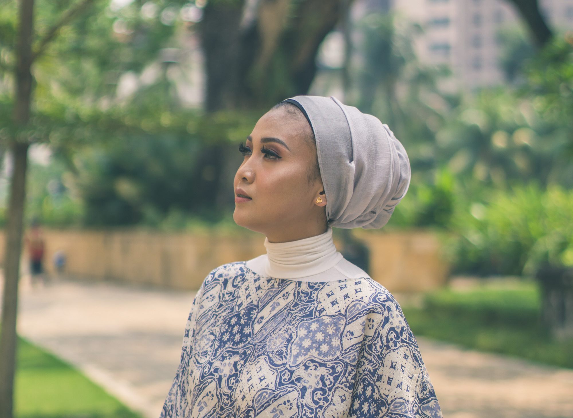 Wanita Asia memakai turban bergaya low bun turban di taman.