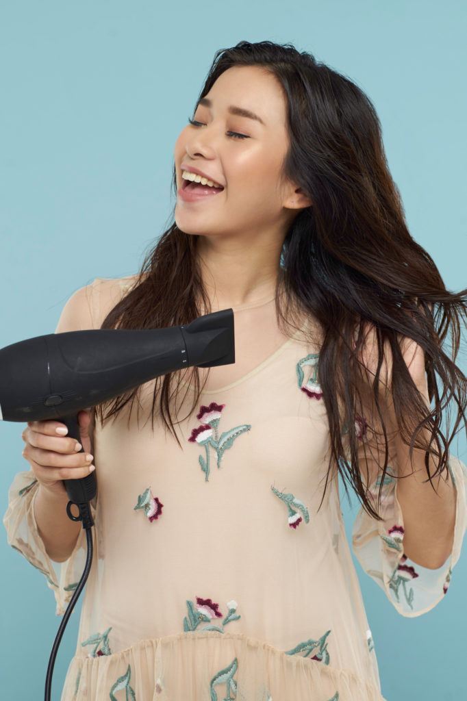 Wanita asia dengan rambut panjang mengeringkan rambut dengan hairdryer - half up half down braid