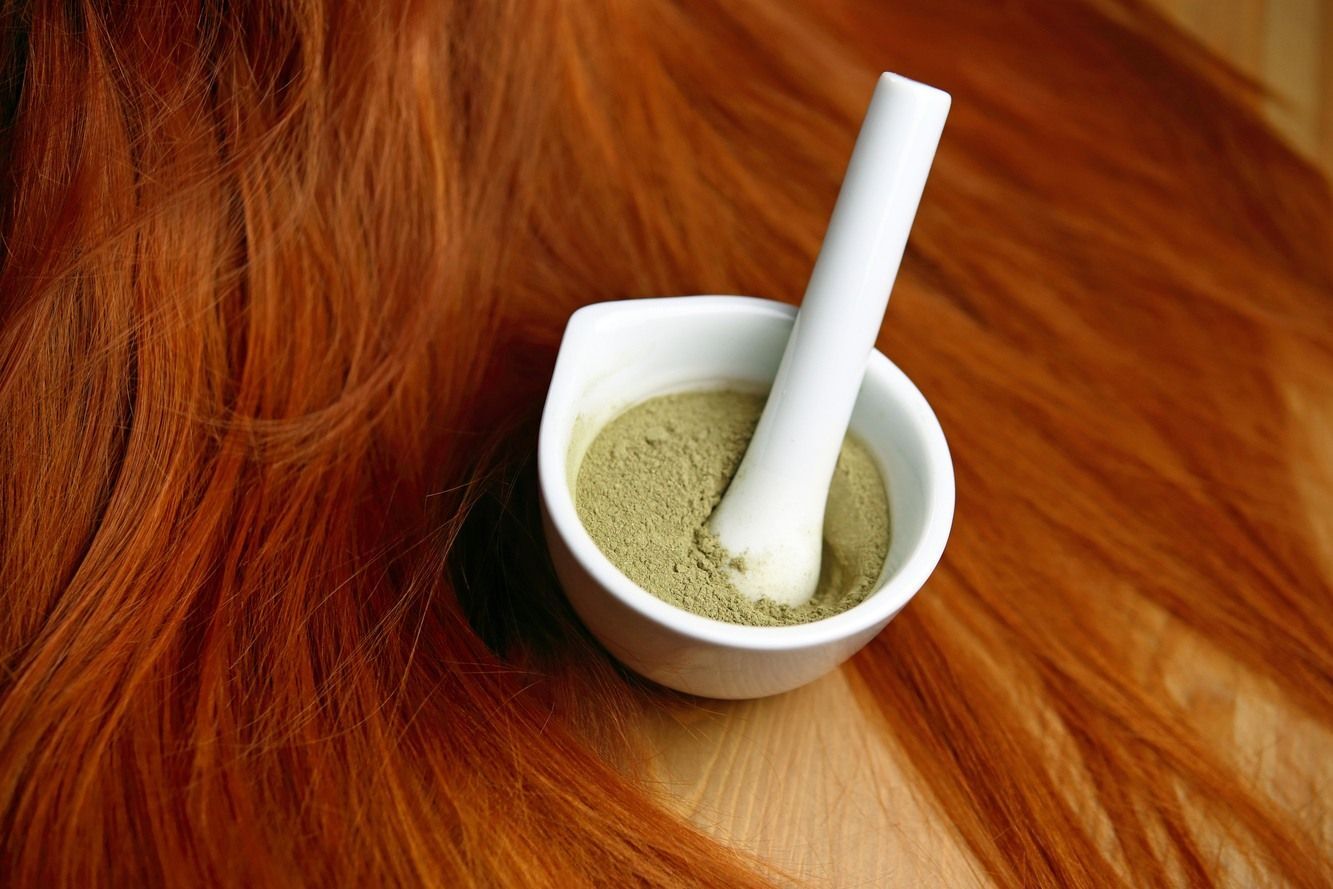 Bubuk henna di dalam wadah mangkuk dan rambut berwarna merah.