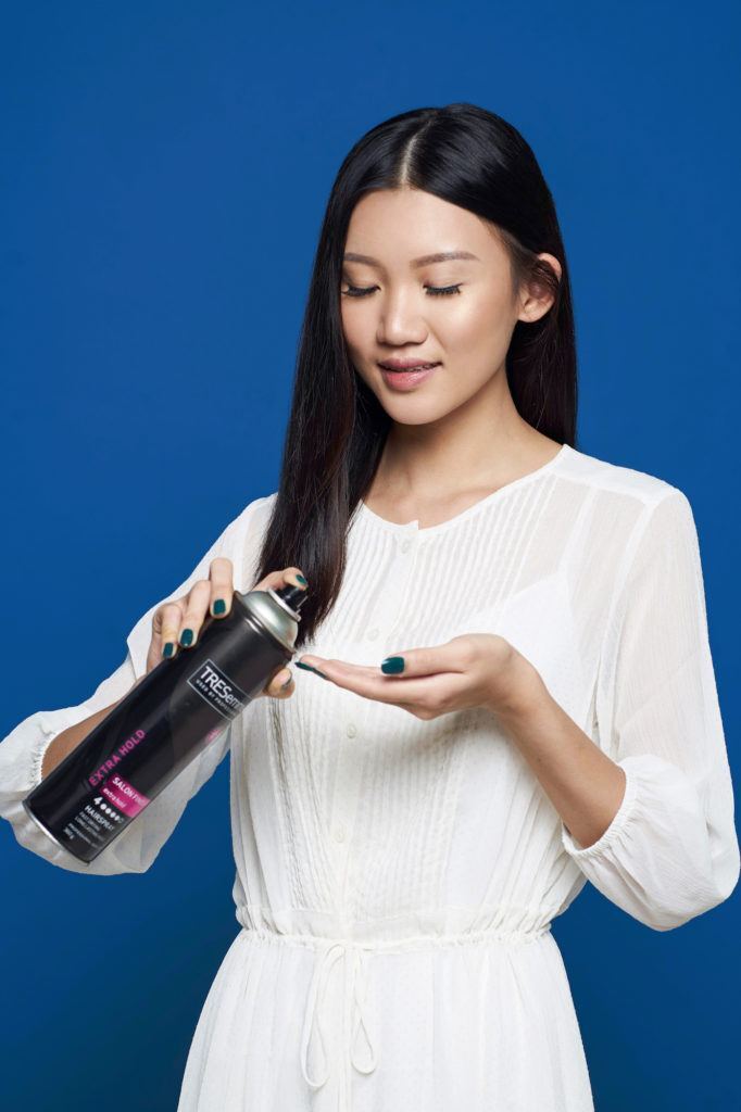 Crown braid - Wanita asia dengan baju putih rambut belah tengah menyemprotkan pada jari.