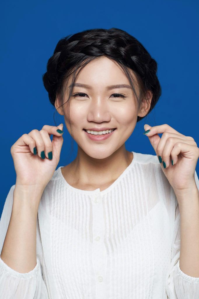 Wanita asia menata rambut gaya crown braid.