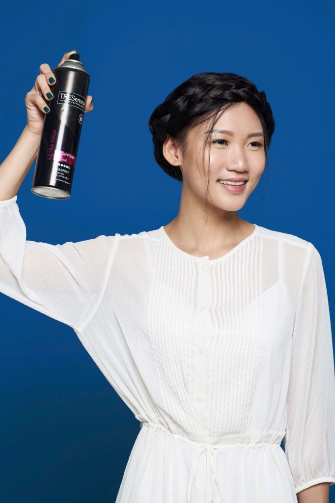 Crown braid – wanita asia menyemprotkan hairspray pada rambut hitamnya.