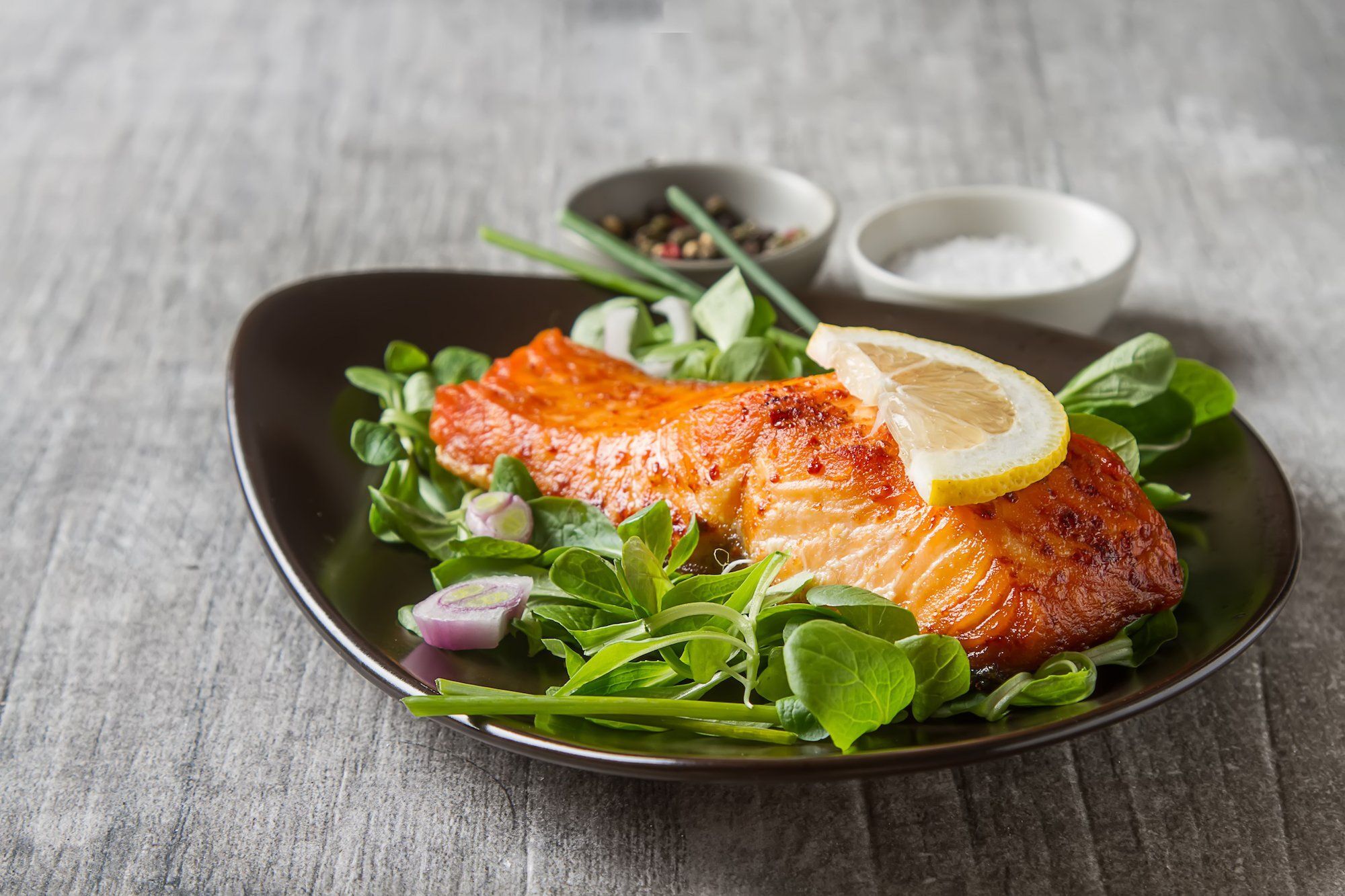Sajian salmon panggang di atas salad hijau