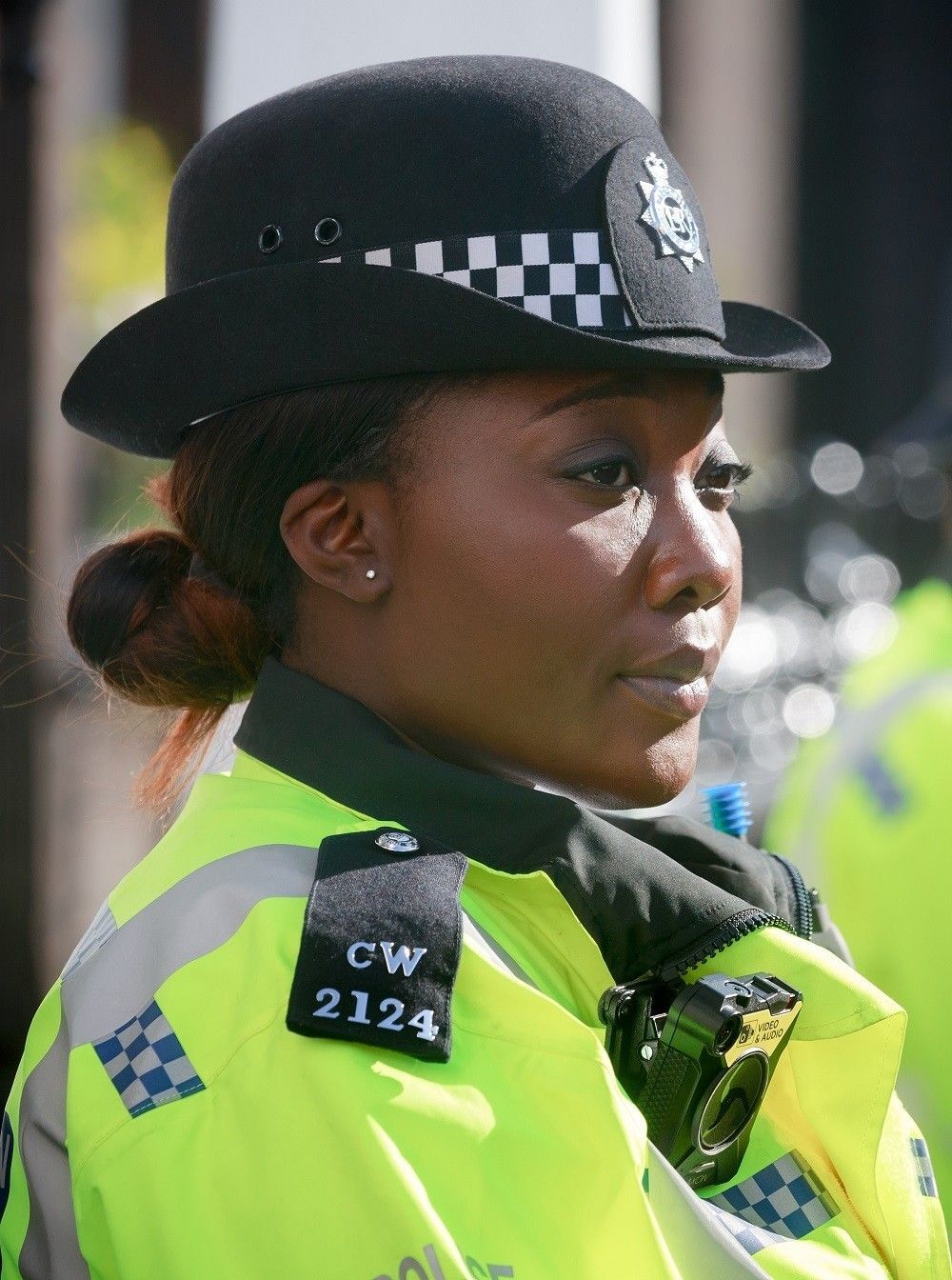 Polisi wanita Inggris sedang bertugas dengan gaya rambut cepol rendah.