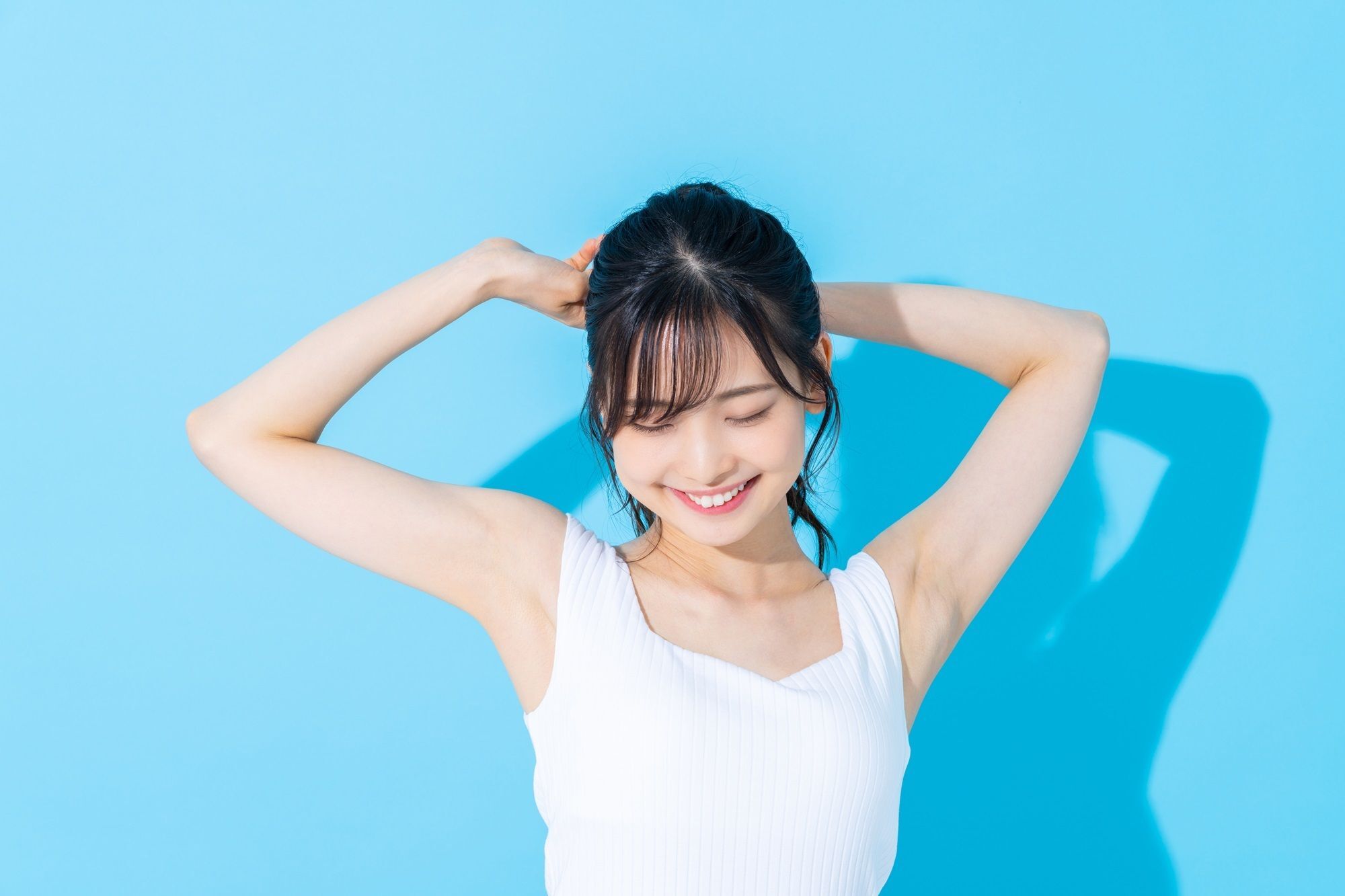 Wanita Asia sedang memegang rambut sambil tersenyum.