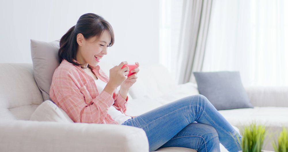 wanita sedang bermain mobile game dari handphone