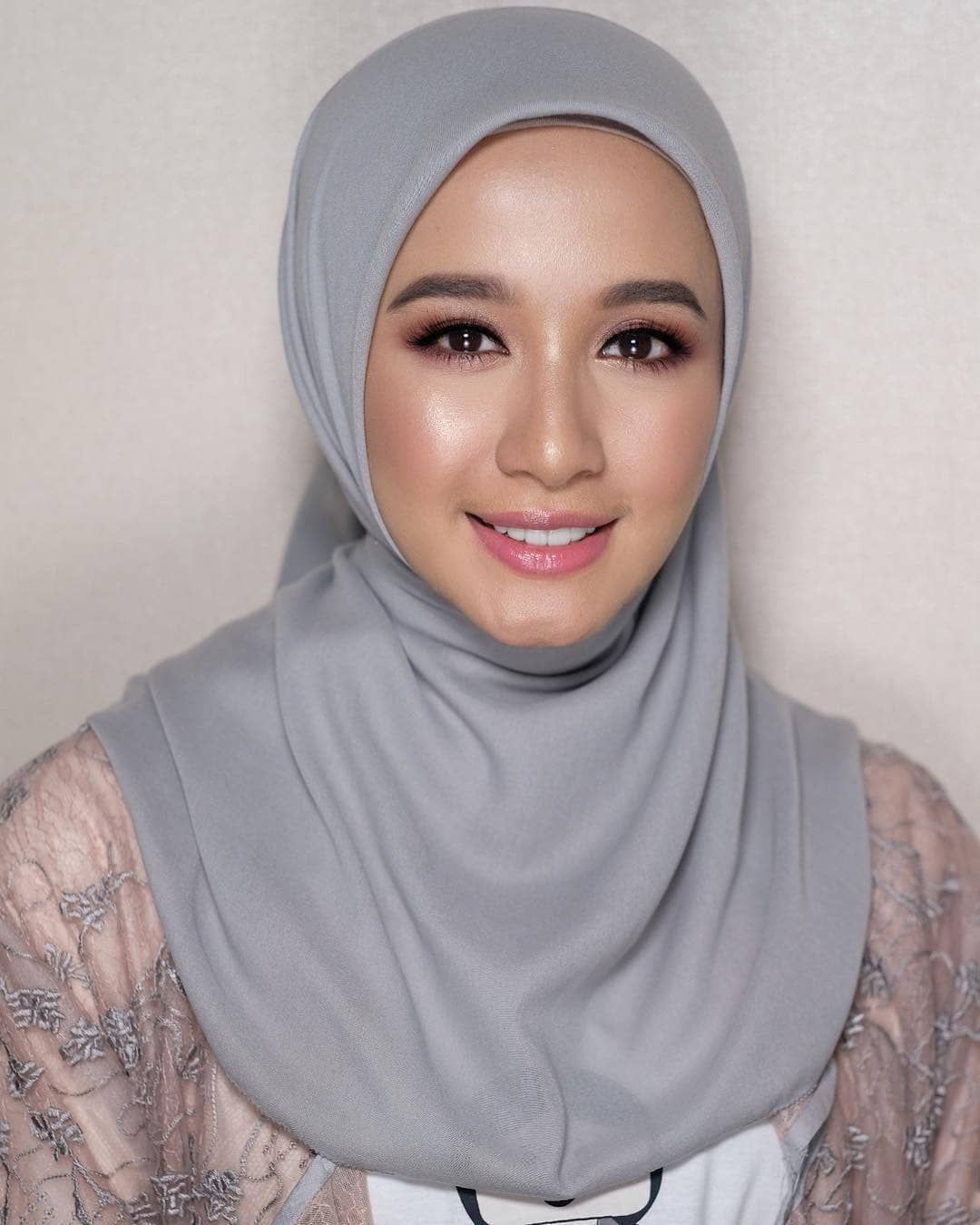 Laudya Cynthia Bella memaki hijab segi empat abu dan tersenyum