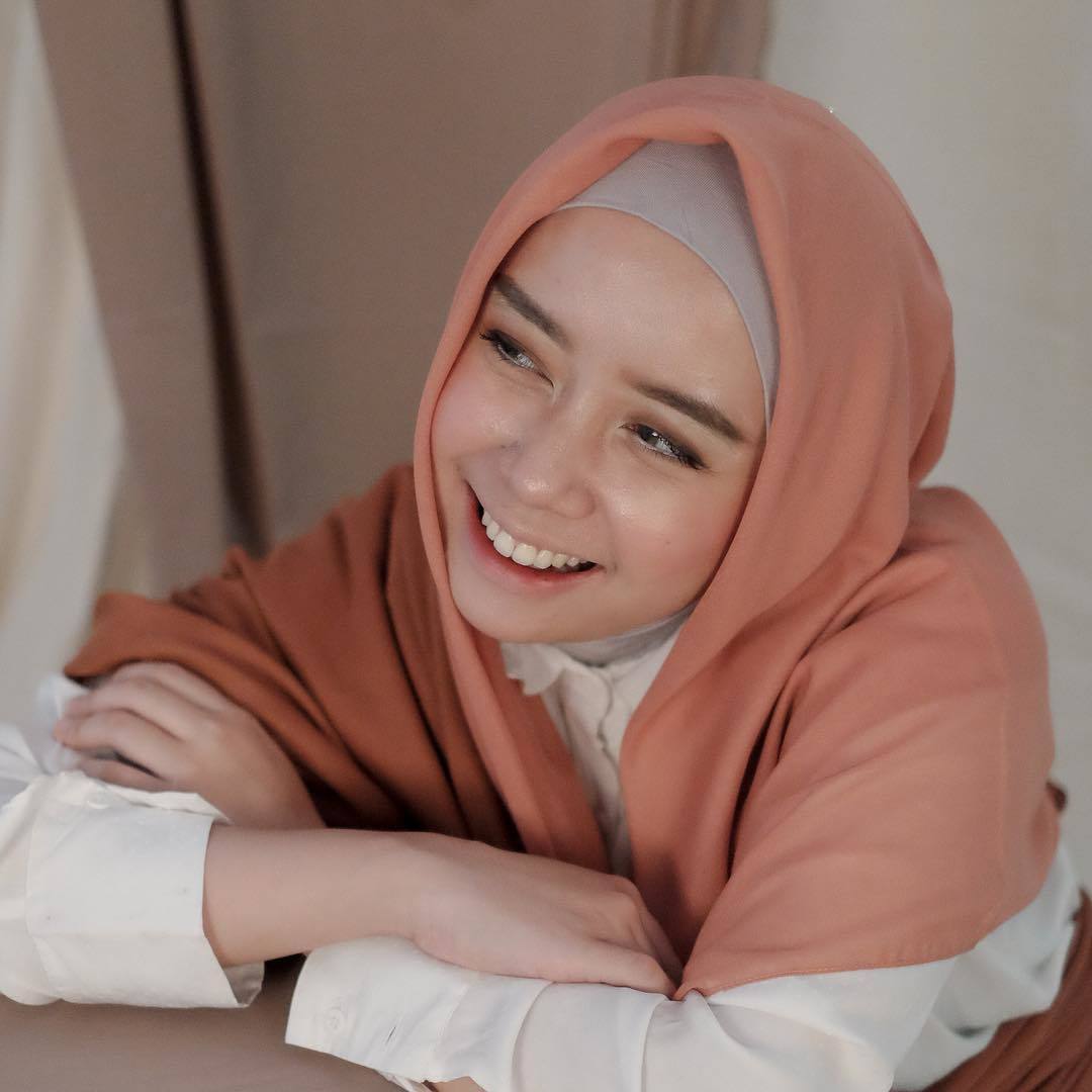 Thata Al Jundiah tersenyum memakai hijab segi empat voile polos warna pink