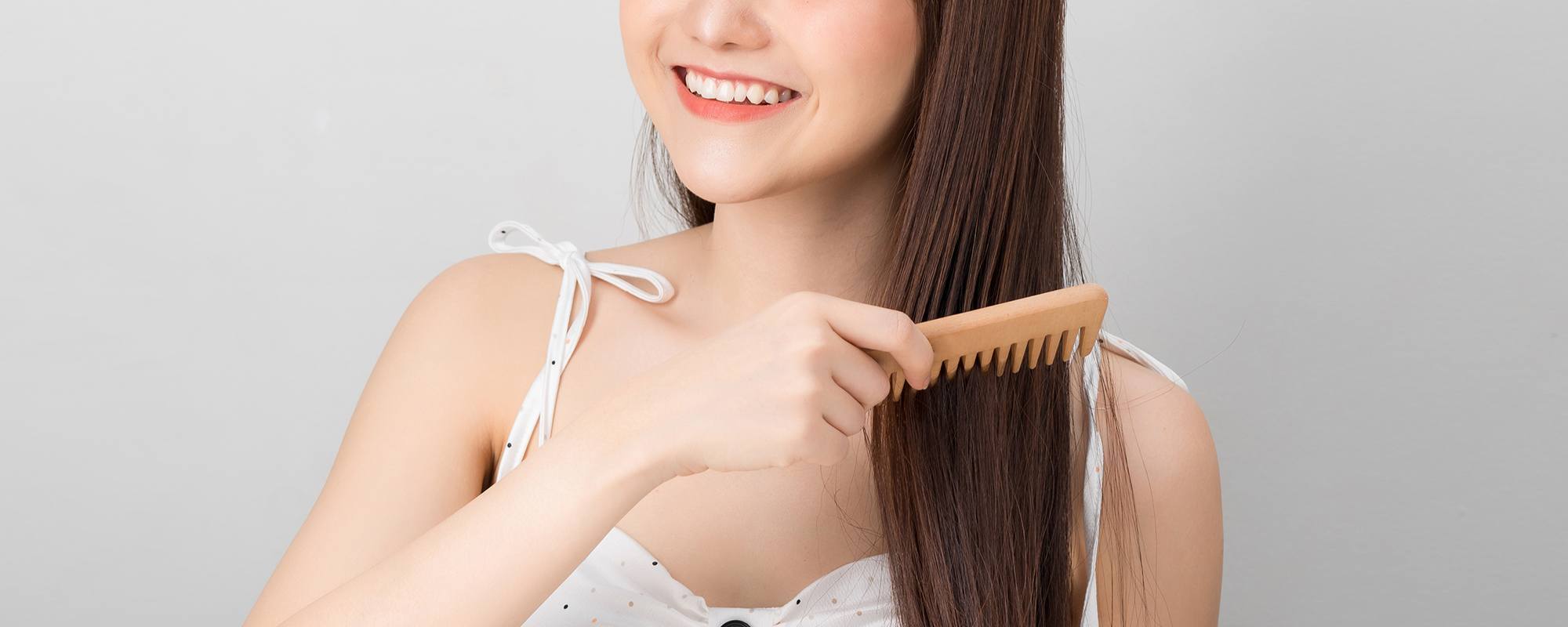 wanita asia sedang menyisir rambut dengan sisir bergigi jarang