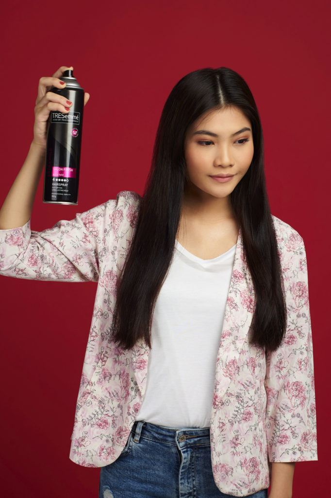 Wanita asia dengan rambut hitam panjang menyemprotkan hairspray - double french twist ponytail