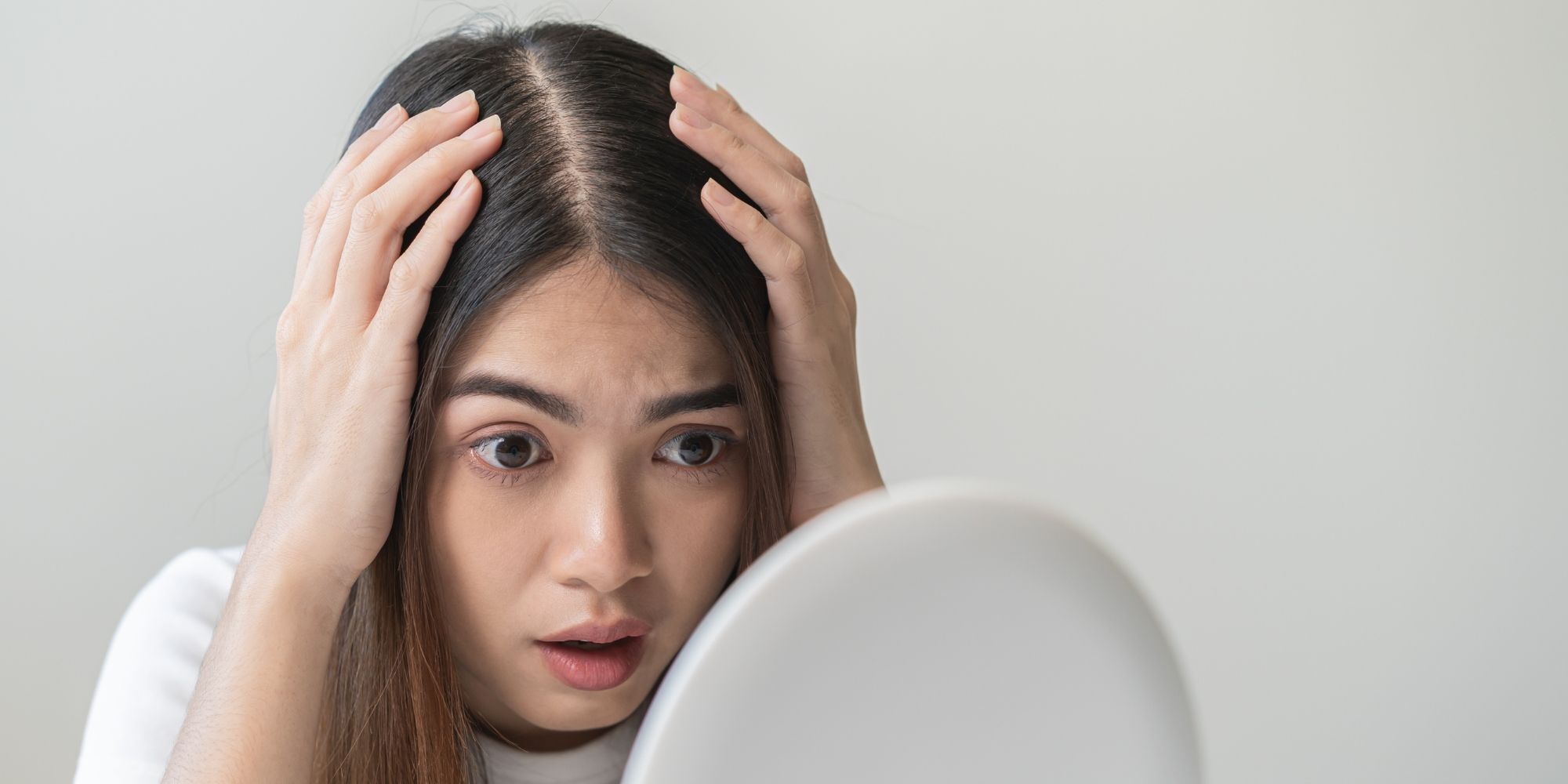 wanita asia sedang melihat cermin untuk memeriksa ketombe