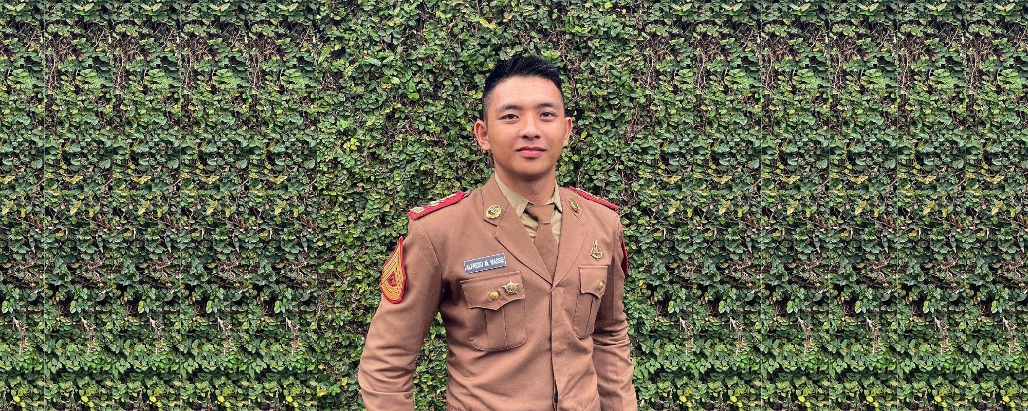 Pria Indonesia memakai baju seragam taruna dengan gaya rambut fade yang bertekstur.