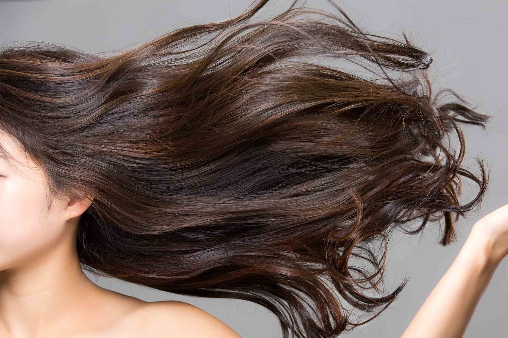 wanita yang sedang mengibaskan rambut panjang berwarna cokelat gelap