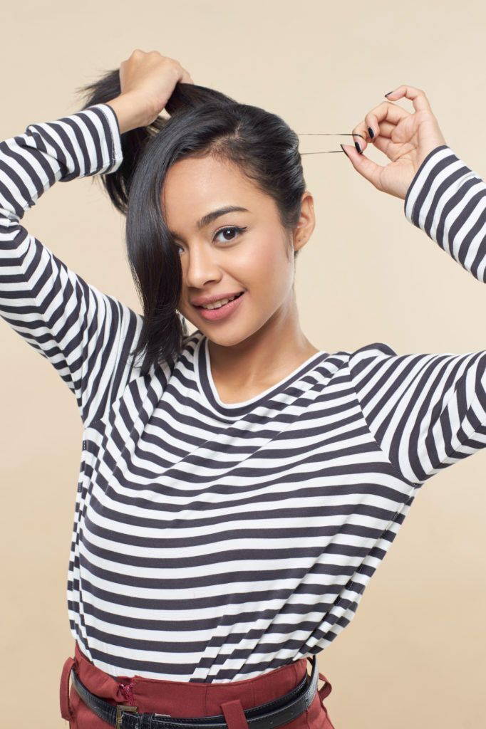 Wanita asia dengan rambut hitam menata gaya rambut pin up hair dengan membentuk ponytail