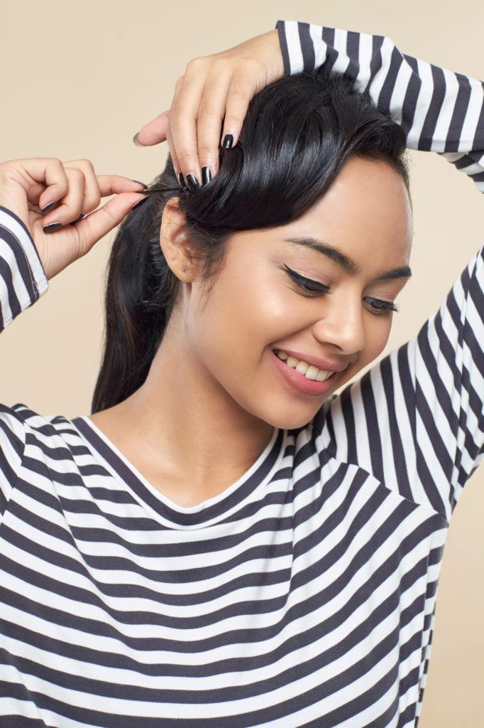 Wanita asia dengan rambut hitam menjepit poni membentuk gaya pin up hair.